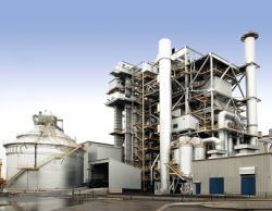 サミット明星パワー社：バイオマス燃料を溜めておく設備（写真左側）より抽出された木屑を石炭と混焼し、国内最大級の発電能力を誇ります。